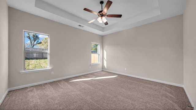 carpeted empty room featuring ceiling fan and a tray ceiling