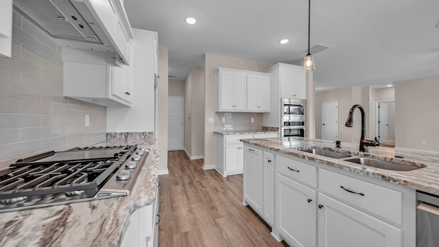 kitchen with light stone countertops, sink, stainless steel appliances, light hardwood / wood-style flooring, and white cabinets