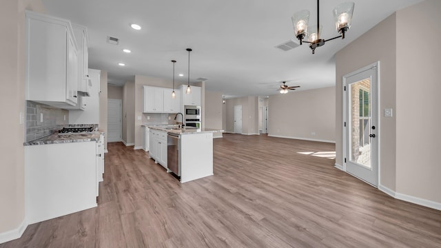 kitchen with white cabinetry, light hardwood / wood-style floors, decorative light fixtures, a kitchen island with sink, and ceiling fan with notable chandelier