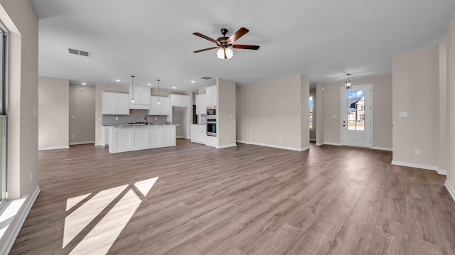 unfurnished living room with ceiling fan and light wood-type flooring