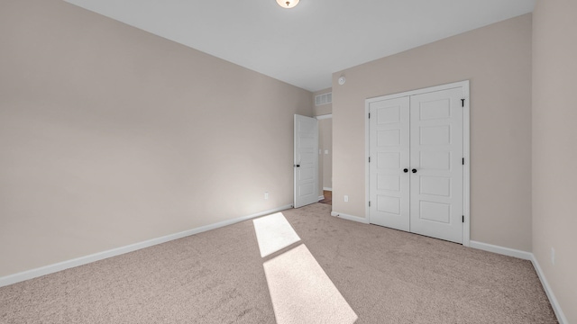 unfurnished bedroom featuring light colored carpet and a closet