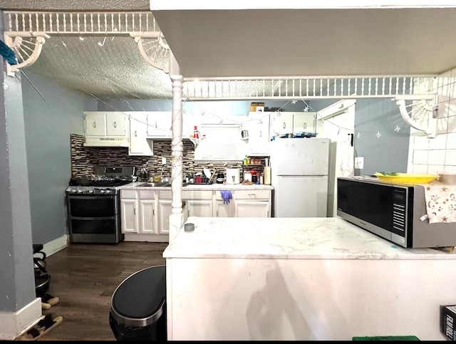 kitchen with white cabinets, appliances with stainless steel finishes, dark wood-type flooring, and tasteful backsplash