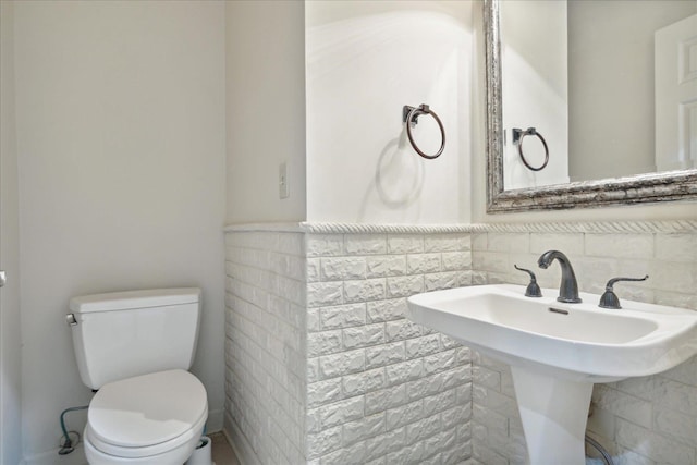 bathroom with tile walls and toilet