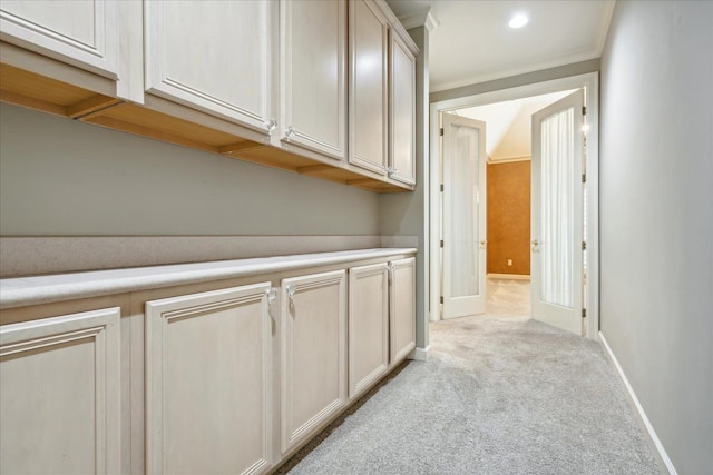 corridor featuring ornamental molding and light carpet