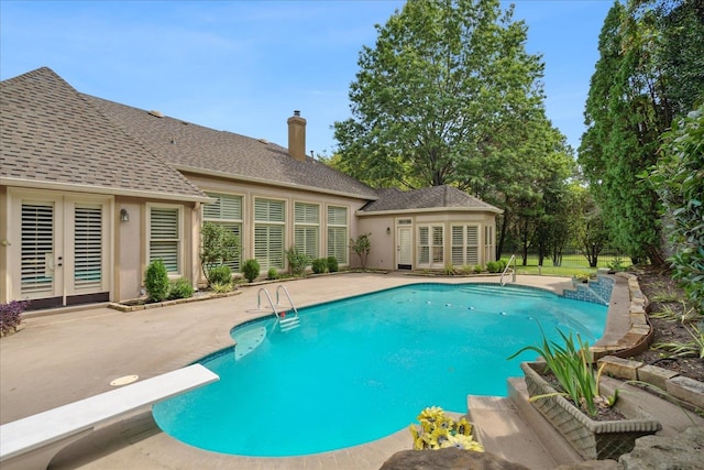 view of swimming pool with a diving board, french doors, and a patio area