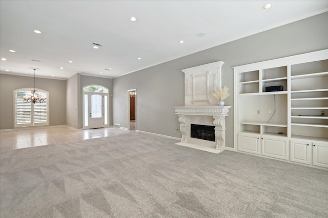 unfurnished living room with light carpet, a notable chandelier, a premium fireplace, and french doors