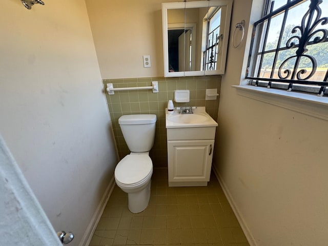 bathroom with tile walls, tile patterned flooring, vanity, and toilet