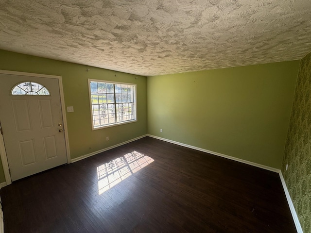 foyer entrance with baseboards, a textured ceiling, and dark wood-type flooring