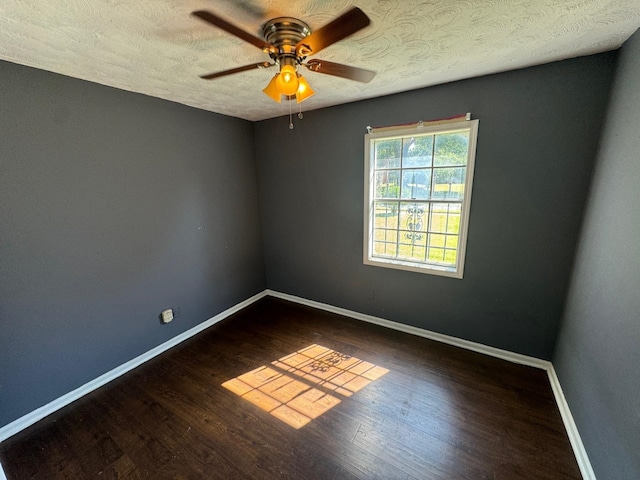 empty room featuring ceiling fan, dark wood-type flooring, and a textured ceiling