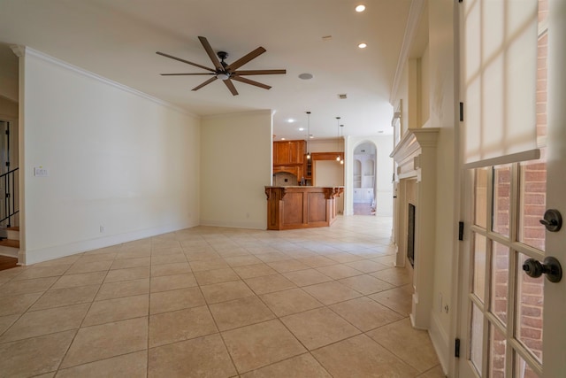 unfurnished living room with ceiling fan, light tile patterned floors, and ornamental molding