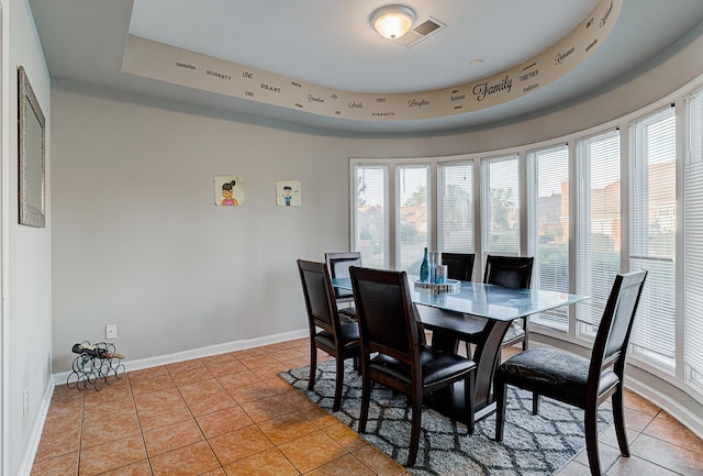 dining area featuring light tile patterned floors and a raised ceiling