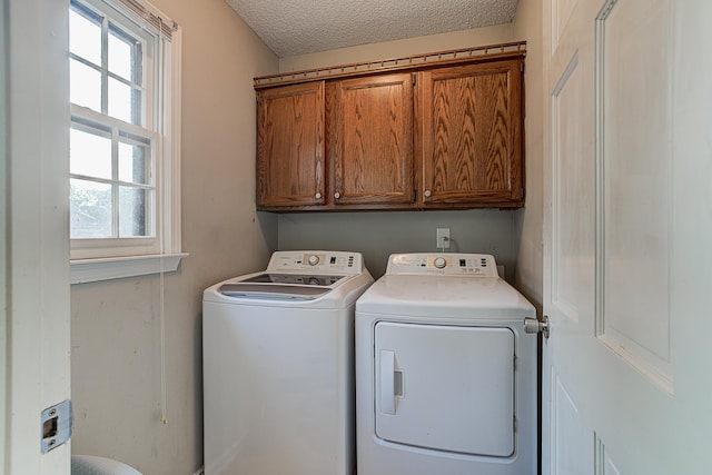 washroom featuring a textured ceiling, cabinets, and washing machine and clothes dryer