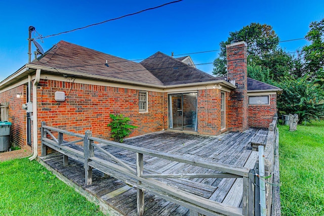 rear view of house featuring a wooden deck and a yard