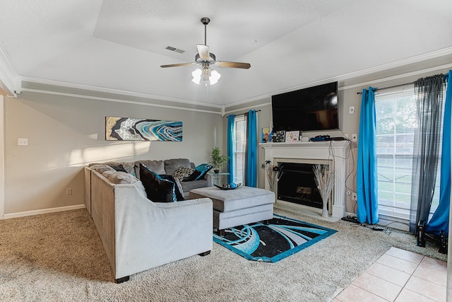 living room with ceiling fan, light tile patterned flooring, crown molding, and a tray ceiling