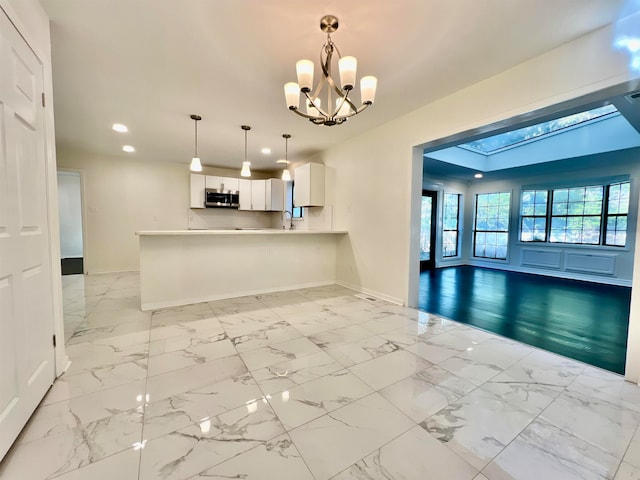 interior space featuring an inviting chandelier, vaulted ceiling with skylight, and sink