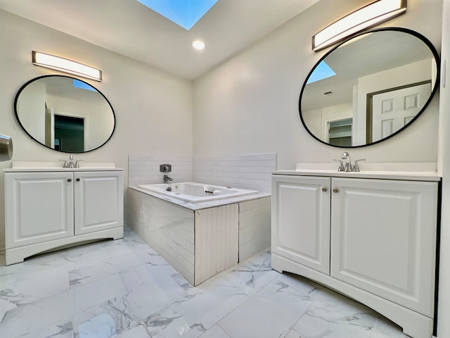 bathroom featuring a skylight, vanity, and tiled bath