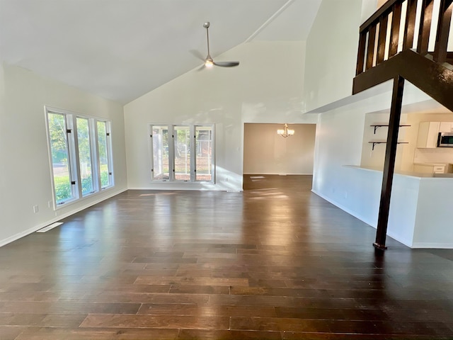 unfurnished living room featuring dark hardwood / wood-style floors, a chandelier, and high vaulted ceiling