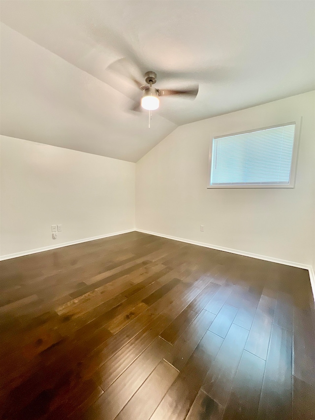 empty room featuring dark hardwood / wood-style floors, vaulted ceiling, and ceiling fan