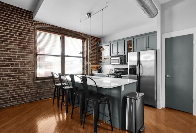 kitchen featuring brick wall, a breakfast bar area, pendant lighting, black appliances, and dark hardwood / wood-style floors