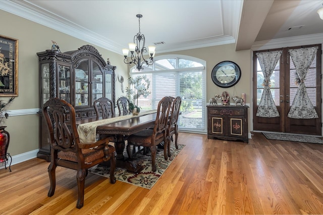 dining room with hardwood / wood-style flooring, crown molding, and a chandelier