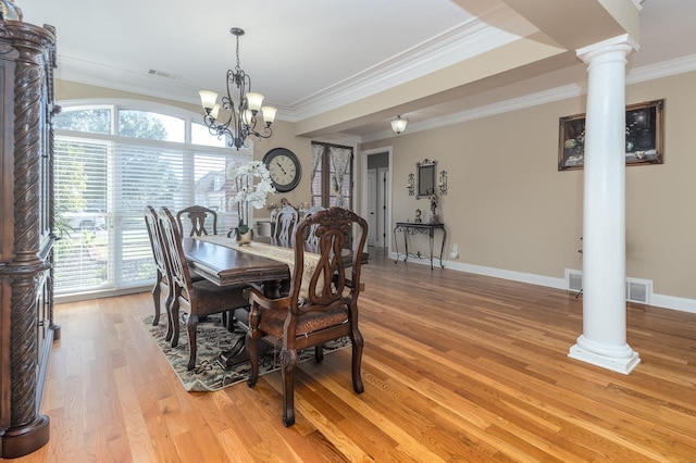 dining room featuring a notable chandelier, light hardwood / wood-style floors, crown molding, and ornate columns