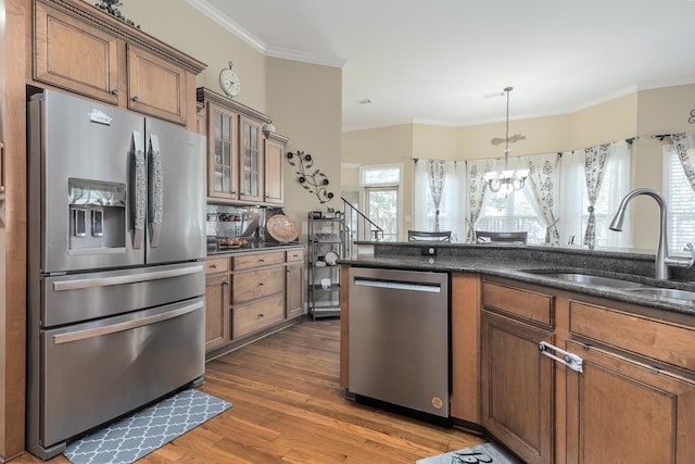 kitchen with pendant lighting, dark wood-type flooring, stainless steel appliances, a notable chandelier, and crown molding