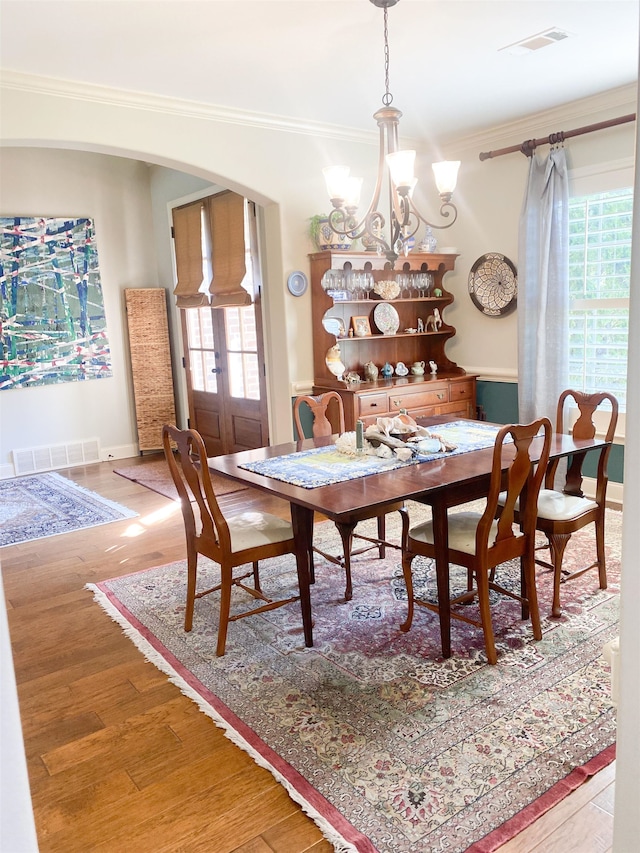 dining area with hardwood / wood-style flooring, crown molding, plenty of natural light, and an inviting chandelier