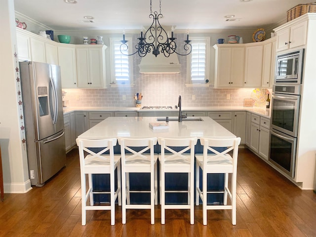 kitchen featuring stainless steel appliances, a breakfast bar area, a center island with sink, and dark hardwood / wood-style flooring