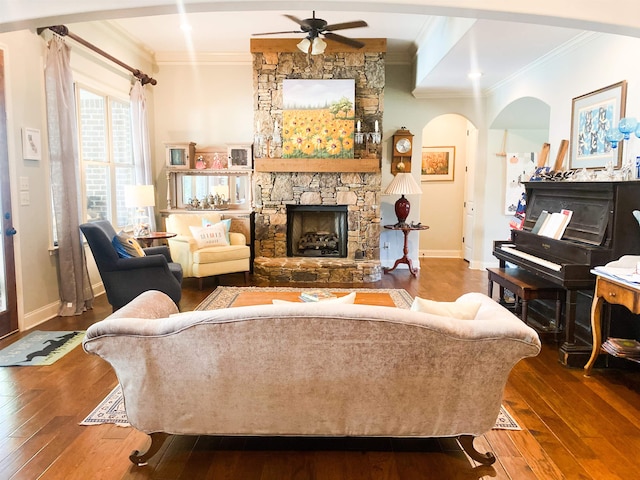 living room featuring wood-type flooring, a fireplace, ornamental molding, and ceiling fan