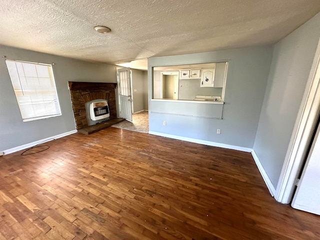 unfurnished living room with wood-type flooring, a textured ceiling, and heating unit