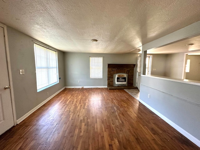 unfurnished living room featuring hardwood / wood-style flooring, heating unit, a fireplace, and a textured ceiling