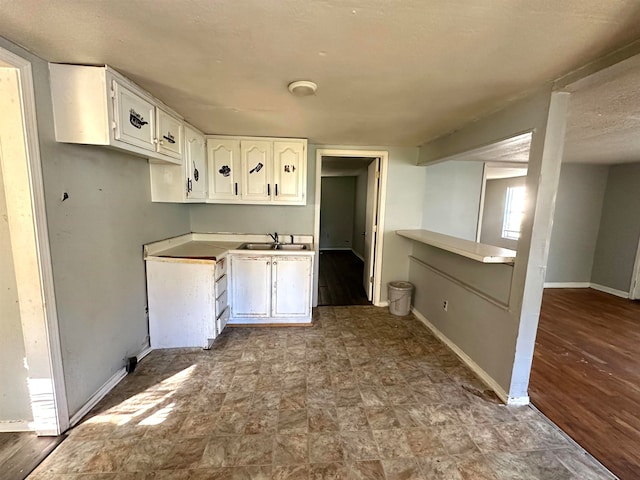 kitchen with white cabinetry, sink, light hardwood / wood-style floors, and a textured ceiling