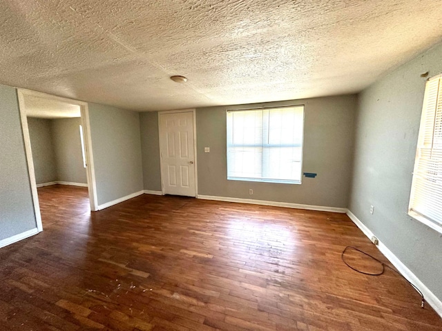 unfurnished room with dark hardwood / wood-style flooring and a textured ceiling