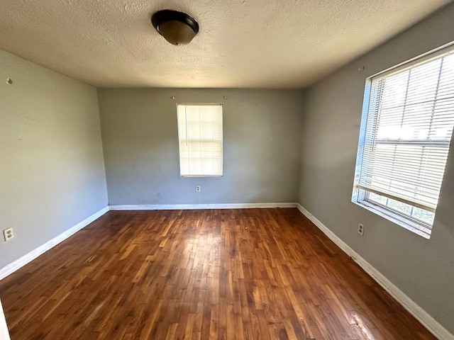 empty room with dark wood-type flooring and a textured ceiling