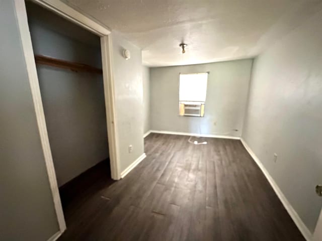 unfurnished bedroom with a closet, cooling unit, and dark wood-type flooring