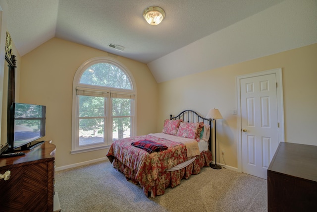 carpeted bedroom with a textured ceiling and vaulted ceiling