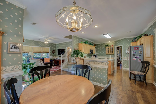 dining space featuring ceiling fan with notable chandelier, crown molding, and dark wood-type flooring