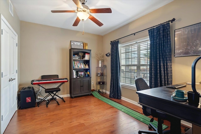 office with light wood-type flooring and ceiling fan