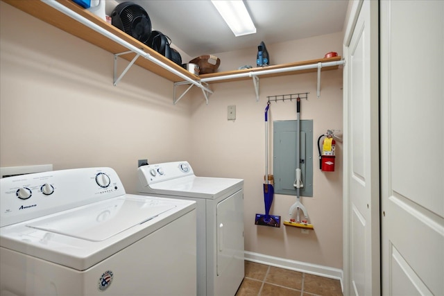 clothes washing area with washing machine and dryer, electric panel, and dark tile patterned floors