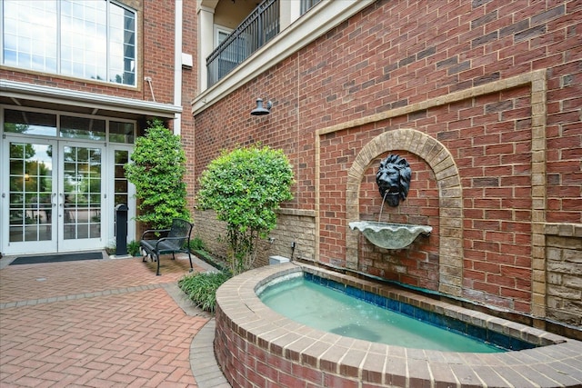 exterior space with french doors, a balcony, and an in ground hot tub