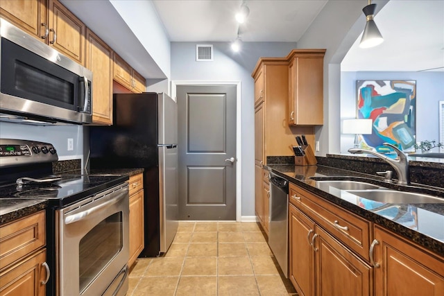 kitchen featuring light tile patterned flooring, stainless steel appliances, sink, and dark stone counters