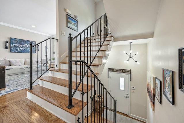 stairs featuring ornamental molding, a high ceiling, hardwood / wood-style flooring, and a chandelier