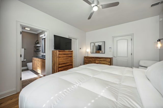 bedroom featuring ceiling fan, crown molding, ensuite bathroom, dark wood-type flooring, and a closet