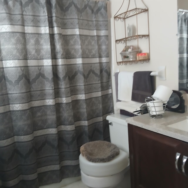 bathroom with walk in shower, vanity, and toilet