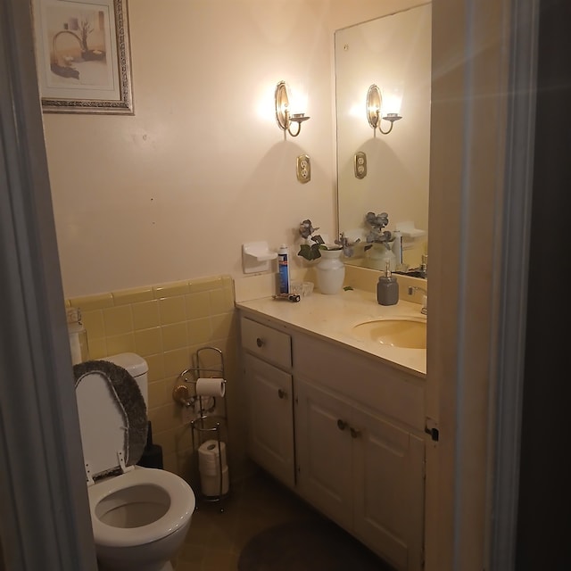 bathroom with tile walls, vanity, toilet, and tile patterned floors