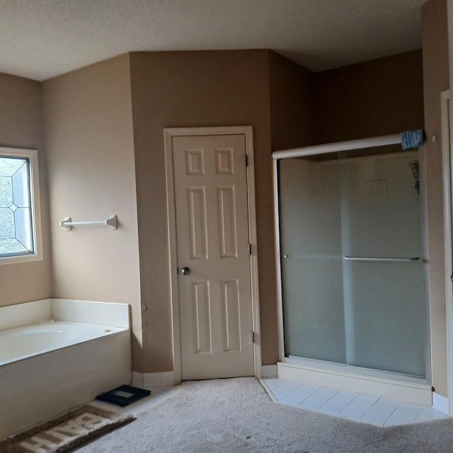 bathroom featuring a textured ceiling and shower with separate bathtub