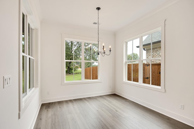 unfurnished dining area featuring wood-type flooring, an inviting chandelier, and crown molding