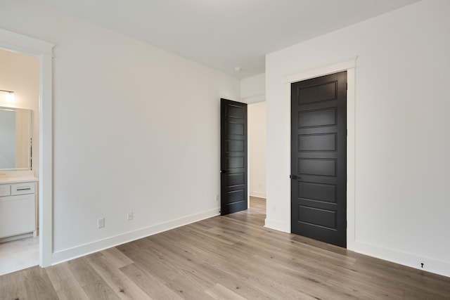 unfurnished bedroom featuring light hardwood / wood-style flooring and connected bathroom