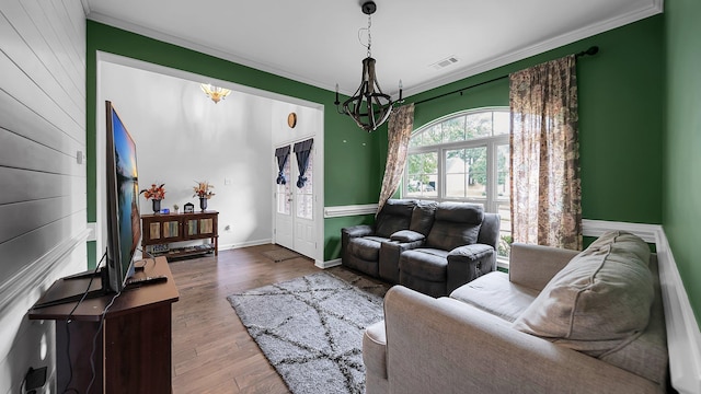 living room with wood-type flooring, crown molding, and an inviting chandelier