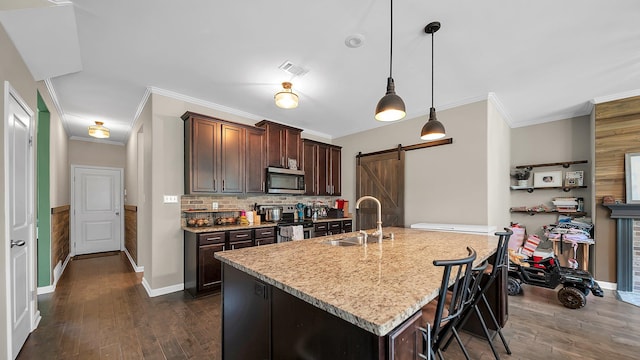 kitchen with sink, stainless steel appliances, hanging light fixtures, a barn door, and dark hardwood / wood-style flooring